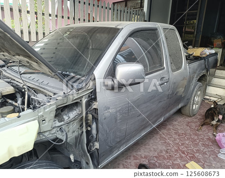 An image shows partially disassembled pickup truck parked garage, with visible dust its surface and tools nearby, creating sense of work progress 125608673