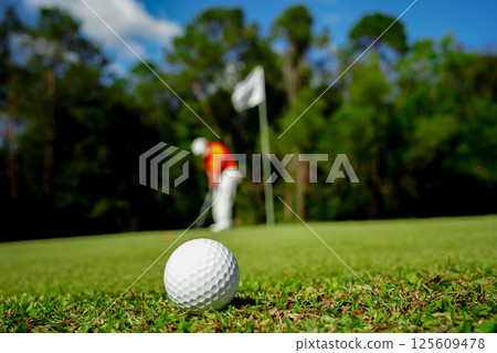 Golf ball on green grass in the evening golf course with sunshine background. 125609478