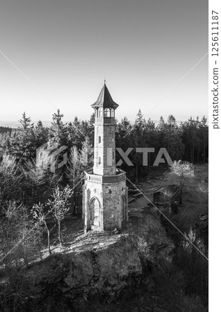Stepanka Lookout Tower stands majestically on a spring morning in Korenov, surrounded by lush trees. The clear sky enhances the tower's historical architecture, inviting exploration and admiration. Stepanka Lookout Tower stands majestically on a spring morning in Korenov, surrounded by lush trees. The clear sky enhances the tower's historical architecture, inviting exploration and admiration. 125611187