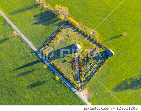 Aerial view of Tesarov Chapel nestled in the Jizera Mountains, showcasing a small graveyard and lush green landscapes of Korenov, revealing serene rural charm and historical significance. 125611200