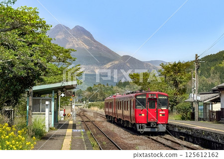 Minami-Yufu Station and a red train in spring with Mount Yufu in the background Minami-Yufu Station and a red train in spring with Mount Yufu in the background 125612162