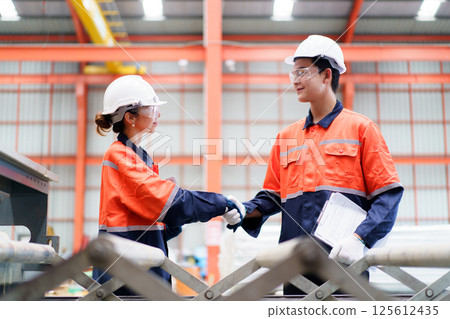 Team of Asian mechanical engineers is having a discussion inside the factory, with the chief engineer talking to his team. Engineer is briefing his team in the morning before they begin their work. 125612435