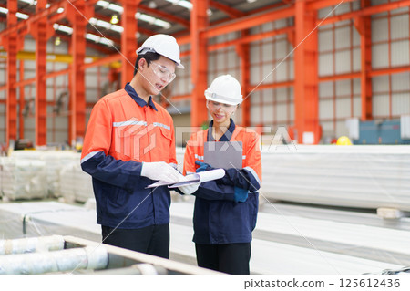 Team of Asian mechanical engineers is having a discussion inside the factory, with the chief engineer talking to his team. Engineer is briefing his team in the morning before they begin their work. Team of Asian mechanical engineers is having a discussion inside the factory, with the chief engineer talking to his team. Engineer is briefing his team in the morning before they begin their work. 125612436