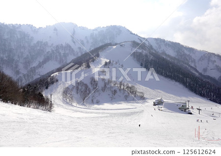 Sunlit ski resort with well-maintained ski runs and lifts 125612624