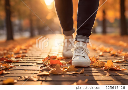 white sneakers on the grass covered with fall foliage 125613426