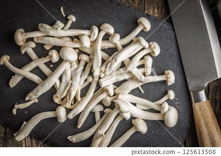 Raw white shimeji mushrooms on cutting board. Top view. Raw white shimeji mushrooms on cutting board. Top view. 125613508