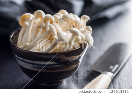 Raw white shimeji mushrooms in bowl on black table. 125613511