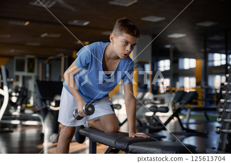 Teenage boy with slender weak body training with inspiration at gym 125613704