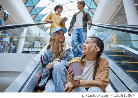 Happy carefree teenagers group riding escalator in shopping mall 125613864