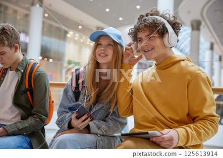 Teen boy sharing favorite music track in headphones to girl friend 125613914