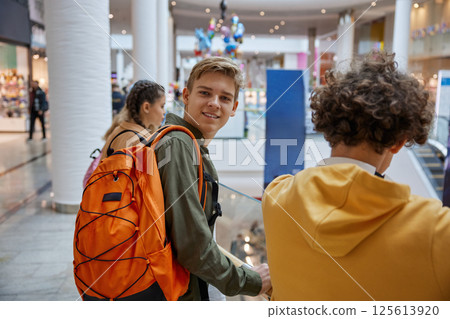 Excited teenage boy looking at camera while entertaining at shopping center Excited teenage boy looking at camera while entertaining at shopping center 125613920