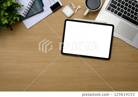 Top view of blank digital tablet screen, laptop, coffee cup and earphones on wooden desk Top view of blank digital tablet screen, laptop, coffee cup and earphones on wooden desk 125614153