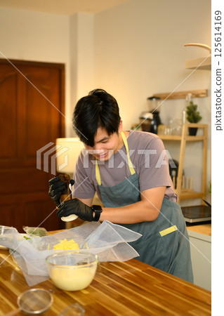 Smiling man seasoning churned butter with pepper, preparing to homemade compound butter Smiling man seasoning churned butter with pepper, preparing to homemade compound butter 125614169