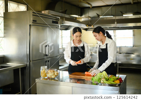 Female culinary student preparing fresh vegetables during a cooking class 125614242