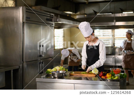 Focused culinary student preparing ingredients during a cooking class 125614268