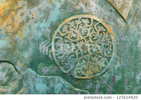 Weathered and textured surface featuring an intricate circular decoration 125614920