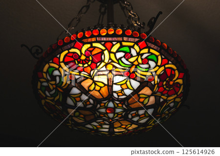 A vibrant close-up of a stained glass ceiling light featuring intricate patterns A vibrant close-up of a stained glass ceiling light featuring intricate patterns 125614926