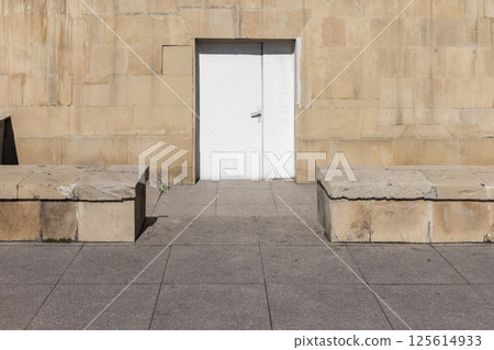 A simple white door set into a textured stone wall, background photo A simple white door set into a textured stone wall, background photo 125614933