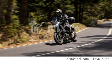 Wide Shot of a Motorcycle Rider in freeze Motion. Motion Blur Effect. Action Sports Shot of Touring Motorbike. 125614956
