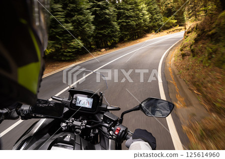 POV Shot of a Man Riding on a Touring Motorcycle. Hands of Motorcyclist on a Handlebars. POV Shot of a Man Riding on a Touring Motorcycle. Hands of Motorcyclist on a Handlebars. 125614960