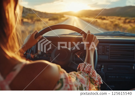Woman driving car towards vibrant desert sunset POV, hands steer into golden light on open highway, beautiful atmospheric travel captures warm sunset mood, perfect adventurous sunset journey. 125615540