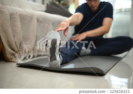 Close up of man stretching his leg muscles during home fitness session 125616321