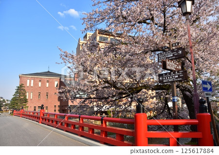 日本岐阜縣高山市的春天。從旅遊景點中橋橋頂看到的景色。盛開的櫻花和周圍的城鎮景觀。美麗的藍天和宮川。 125617884