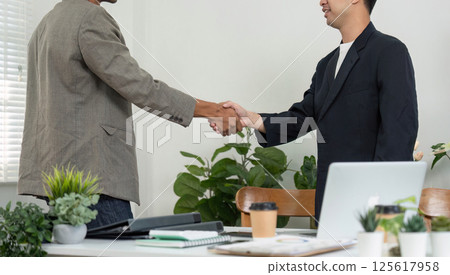 Professional Networking and Agreement. Two men shaking hands in a modern office environment. Professional Networking and Agreement. Two men shaking hands in a modern office environment. 125617958