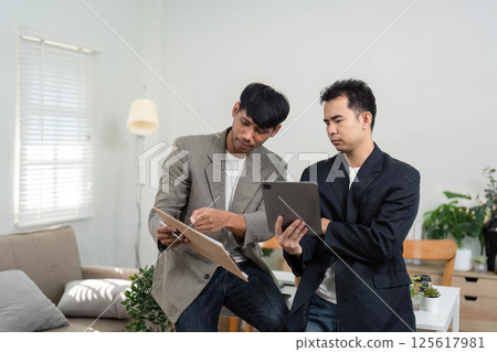 Business Collaboration and Insight Sharing. Two professionals reviewing data and discussing strategies in an office. Business Collaboration and Insight Sharing. Two professionals reviewing data and discussing strategies in an office. 125617981