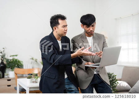 Business Discussion and Collaboration. Two professionals engaging in a serious conversation about project challenges in a modern workspace. Business Discussion and Collaboration. Two professionals engaging in a serious conversation about project challenges in a modern workspace. 125618010