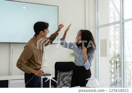 Excitement and Collaboration. Professionals celebrating a breakthrough in sustainable design. 125618021