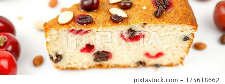 Rich fruitcake with cherries, raisins, and almond toppings served on a white background Rich fruitcake with cherries, raisins, and almond toppings served on a white background 125618662