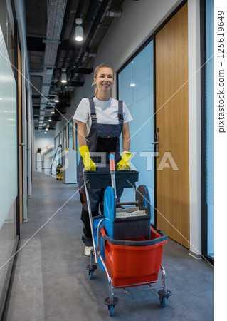 Smiling girl from the cleaning team pushing the cart and going to work place 125619649