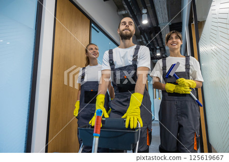 Cleaning team walking in the office corridor with cleaning equipment Cleaning team walking in the office corridor with cleaning equipment 125619667