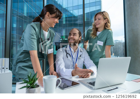 Medical team working together in office using laptop for discussing diagnosis Medical team working together in office using laptop for discussing diagnosis 125619692