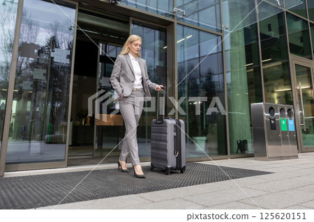 Woman entrepreneur carrying baggage while walking confidently from office Woman entrepreneur carrying baggage while walking confidently from office 125620151