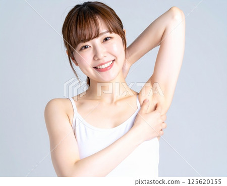 Image of a woman in a tank top raising her arms and armpit hair removal 125620155