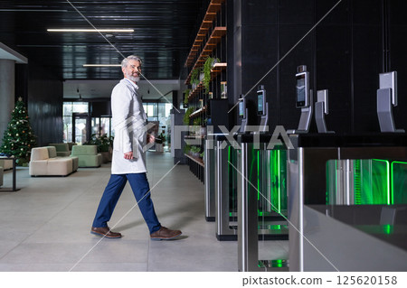 Male doctor going to the security entrance while coming to his working place Male doctor going to the security entrance while coming to his working place 125620158