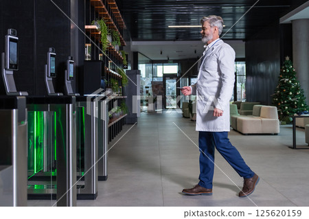 Male doctor going to the security entrance while coming to his working place Male doctor going to the security entrance while coming to his working place 125620159