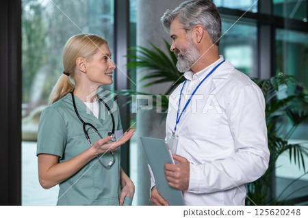Two doctors discussing medical case and looking involved and focused Two doctors discussing medical case and looking involved and focused 125620248