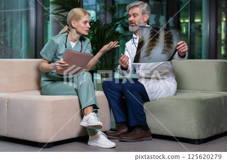 Two doctors sitting next to each other and discussing xray results 125620279