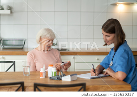 Medical professional giving assistance to elderly patient offering help with disease treatment 125620337