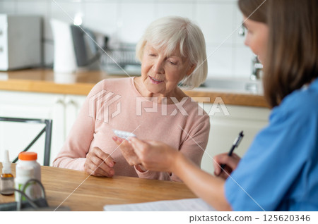 Medical professional giving assistance to elderly patient offering help with disease treatment Medical professional giving assistance to elderly patient offering help with disease treatment 125620346