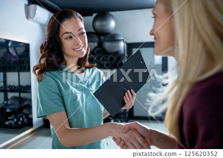 Female patient meeting her doctor in clinic and both looking contented Female patient meeting her doctor in clinic and both looking contented 125620352