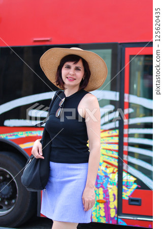 Woman in hat near tourist bus in warm country 125620435