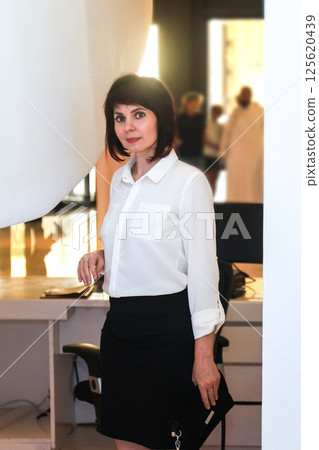 An office worker stands near her workstation with a computer on her desk 125620439