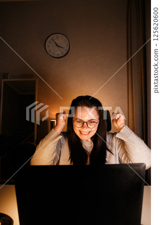 Young businesswoman looking at computer screen and seeing first sales of her small business. Exciting and happy Caucasian woman with laptop. New entrepreneur selling products. 125620600