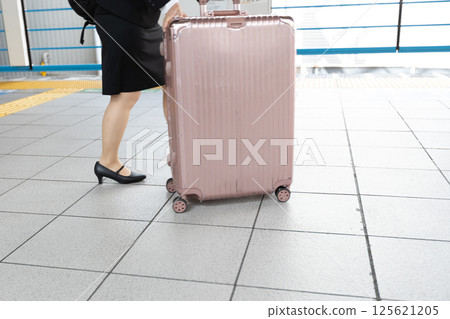 A career woman pushing a pink suitcase 125621205