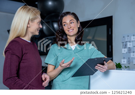 Brunette young doctor talking to a female patient on the results of diagnostics Brunette young doctor talking to a female patient on the results of diagnostics 125621240
