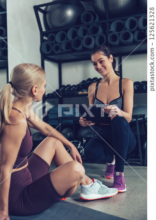 Blonde woman having a conversation with her coach after workout in gym Blonde woman having a conversation with her coach after workout in gym 125621328